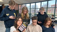 Ungdomar använder mobiltelefoner i en skolmiljö, SVT:s reporter visar skärmen mot kameran.