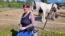Anna-Karin Långström sitter på en rullator framför hästar i en hästhage