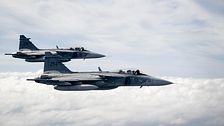 Två stridsflygplan av modell Gripen flyger ovan molntäcket.