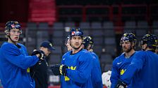 Ishockeyspelare i blå tröjor samtalar under ett träningspass i ishall.