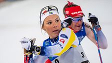 Två längdskidåkare tävlar sida vid sida i färgstarka tävlingsdräkter.