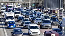 Tät trafik på flerfilig motorväg under en klar dag. Bilar och lastbilar kör i köbildning.