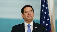 Marco Rubio i kostym framför amerikansk flagga.