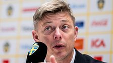 Jon Dahl Tomasson på en presskonferens med en mikrofon framför sig.