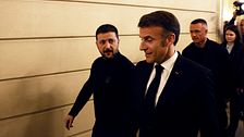 Personer i kostym går bredvid en man i en korridor, följda av fler människor.