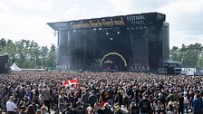 Festivalbesökare i stort publikhav framför en scen på Sweden Rock Festival.