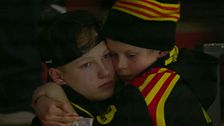 Person i publiken i randig mössa kramar om någon i liknande färger.