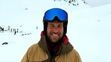 Person med skidkläder och hjälm på snötäckt fjäll.