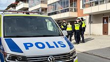 Polisbil och flera poliser utanför ett flerbostadshus.