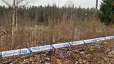 Ett avspärrningsband från polisen kring ett naturområde med buskar och träd