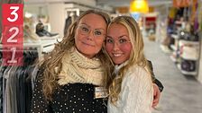 Två personer omfamnade i en butik med kläder i bakgrunden.