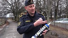 En polisman i uniform visar en lustgastub.