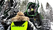 kvinna med reflexväst skogsskördare i skog
