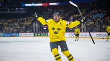 Svensk ishockeyspelare jublar efter mål under match, publik syns i bakgrunden.