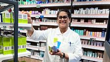 Apotekspersonal sorterar medicinförpackningar på hyllor i ett apotek.