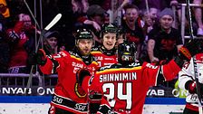 Hockeyspelare firar mål, omgivna av jublande fans i arenan.