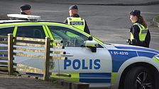 Tre poliser står vid en polisbil i ett bostadsområde.