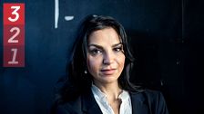 Person i kostym framför mörk bakgrund.