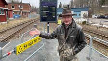 En man i hatt står vid två järnvägsspår.
