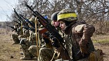 Soldater från Ukraina knäböjer i formation och håller gevär, redo för stridsövning.