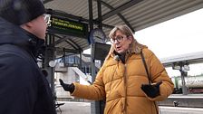 En man och en kvinna pratar med varandra på en tågstation.