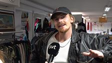 Person i läderjacka i en klädbutik, intervjuas av SVT.