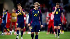 Svenska fotbollsspelare i mörka uniformer går besvikna av planen.