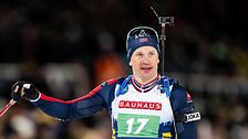 En skidskytt i tävlingskläder med gevär på ryggen. Nummer 17 på bröstet.