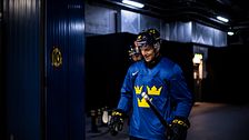 Hockeyspelare i blå Tre Kronor-tröja förbereder sig inför match i en arena.