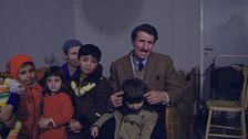 en man i mustasch och kavaj och massa barn
