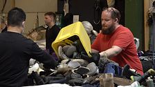 Flera personer sorterar kläder och skor på ett bord.