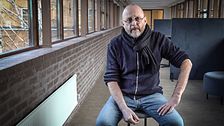 Borlänge kommuns socialchef Tomas Ahlin sitter i en korridor med tegelvägg och fönster.