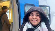 Kvinna med luva står framför ett pendeltåg