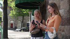 Två unga kvinnor med varsin mobil.