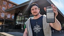 Tor Hettinger  visar upp mobilen i solen på torget i Umeå – en sida från EU-valkompassen syns på skärmen