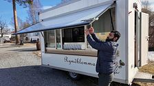 Saed Atiqullah öppnar luckan på en matvagn utomhus. Soligt väder och blå himmel.