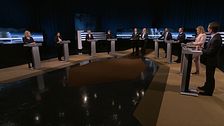 Åtta partiledare står vid podium i en tv-studio inför en partiledardebatt.