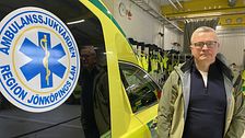 Anders Ingvarsson står bredvid en ambulans från Region Jönköpings län. Han tittar allvarligt in i kameran.