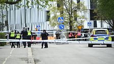 Poliser vid avspärrning på gata, polisbil står parkerad intill avspärrningsband.