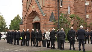 Spelare från Torsby IF tar emot kistan utanför kyrkan