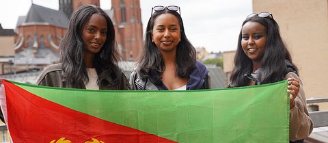 Tre unga tjejer håller Eritreas flagga