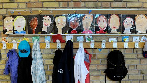 Skolkorridor utanför ett klassrum med kläder på klädhängare och tecknade porträtt av eleverna