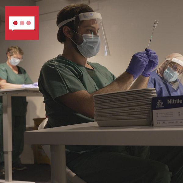 Läkare fyller en kanyl med vaccin från en liten burk.