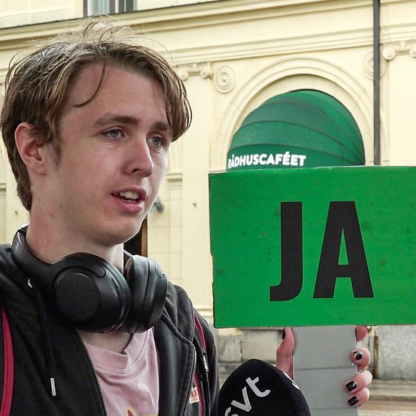 Till vänster en kille med en skylt där det står JA, till höger en tjej med en skylt där det står NEJ