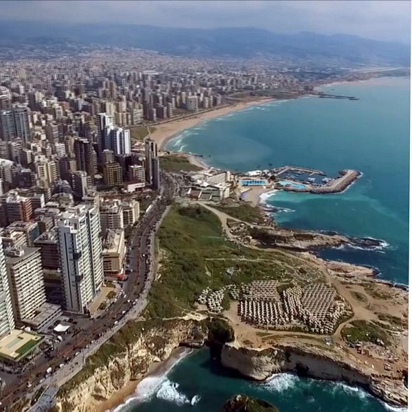 En delad bild som visar två scener: till vänster en vidvinkelbild av Beiruts kustlinje med moderna byggnader och havet, och till höger en närbild av en historisk byggnad med färgglada fönster och detaljrik arkitektur.