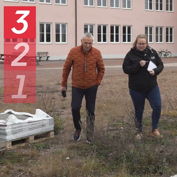 Morabon Ove Hållmarker och SVT:s reporter Ann-Louise Julin går omkring på Strandenområdet i Mora. Det ligger en pall men marksten i gräset och i bakgrunden syns Rosa huset.