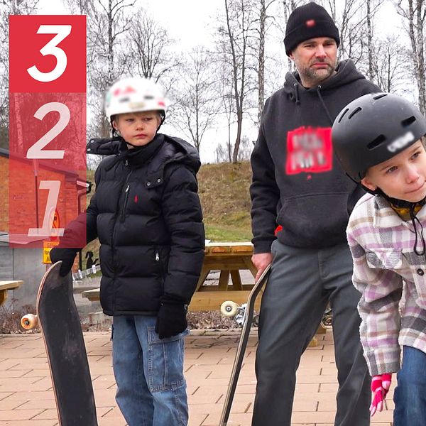 Två barn med hjälm och skateboard i skatepark tillsammans med en vuxen person.