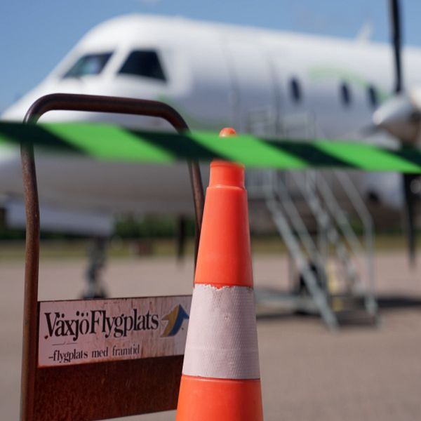 Pernilla Tornéus framför ett flygplan och en avspärrningskona