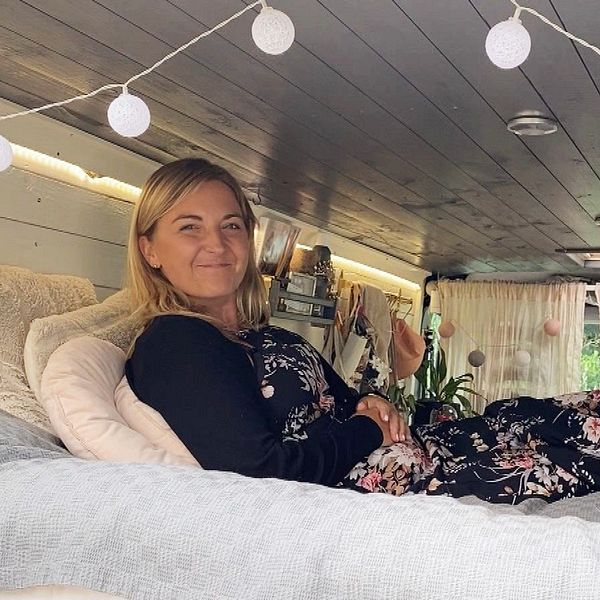 Kvinna ligger på säng i ombyggd van