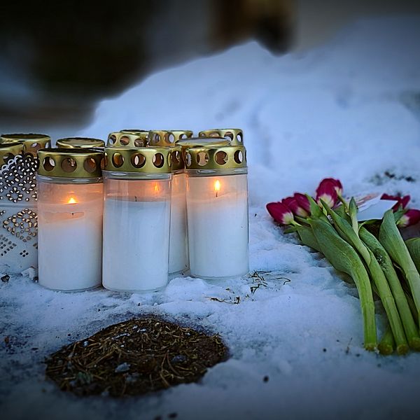 tända gravljus och blommor, en allvarlig kvinna i glasögon